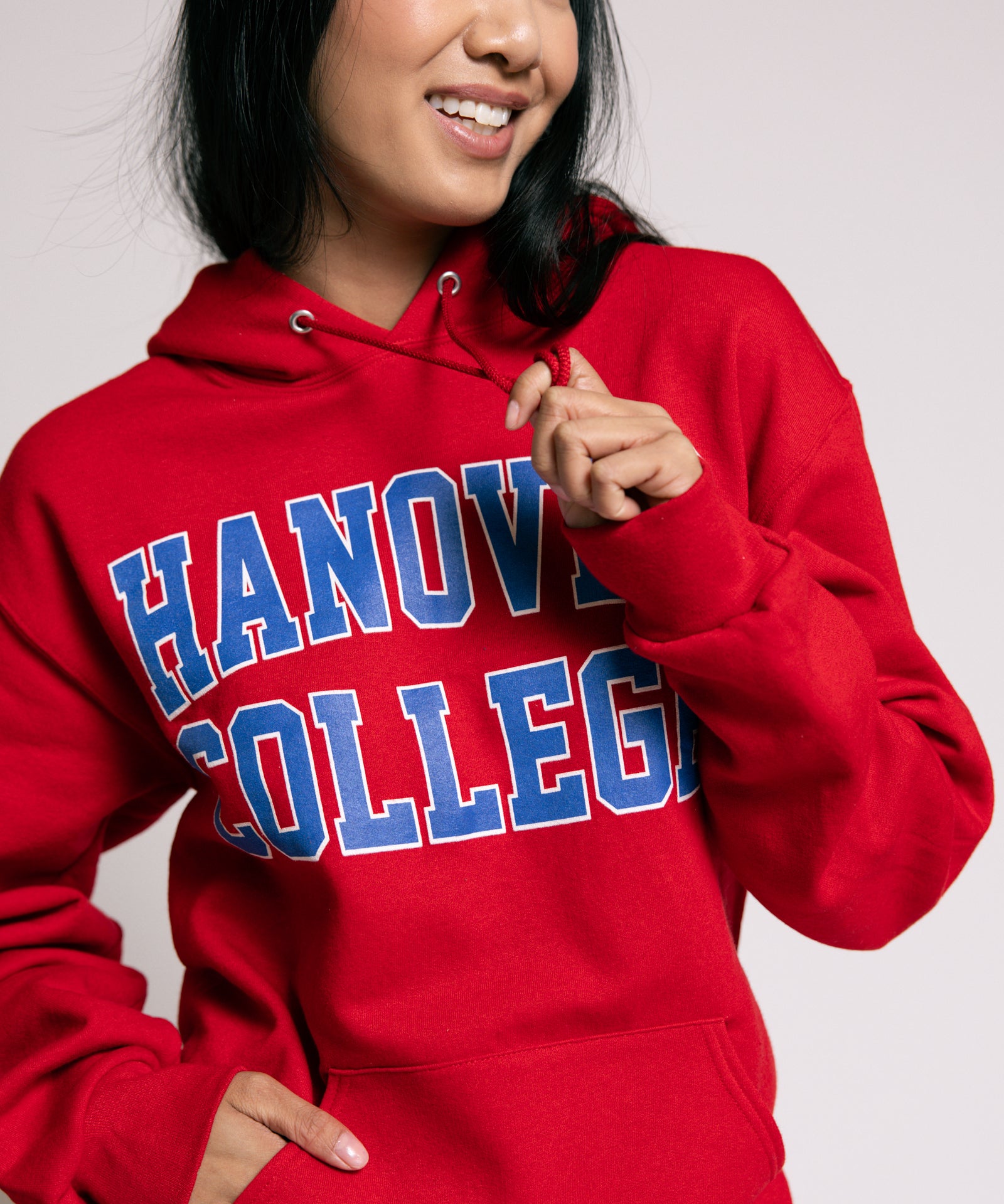 Person wearing a red 'Hanover College' hoodie against a plain background