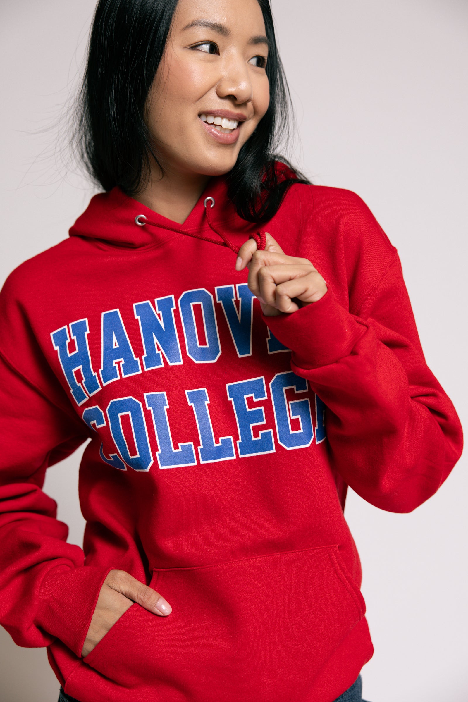 Person wearing a red 'Hanover College' hoodie against a plain background