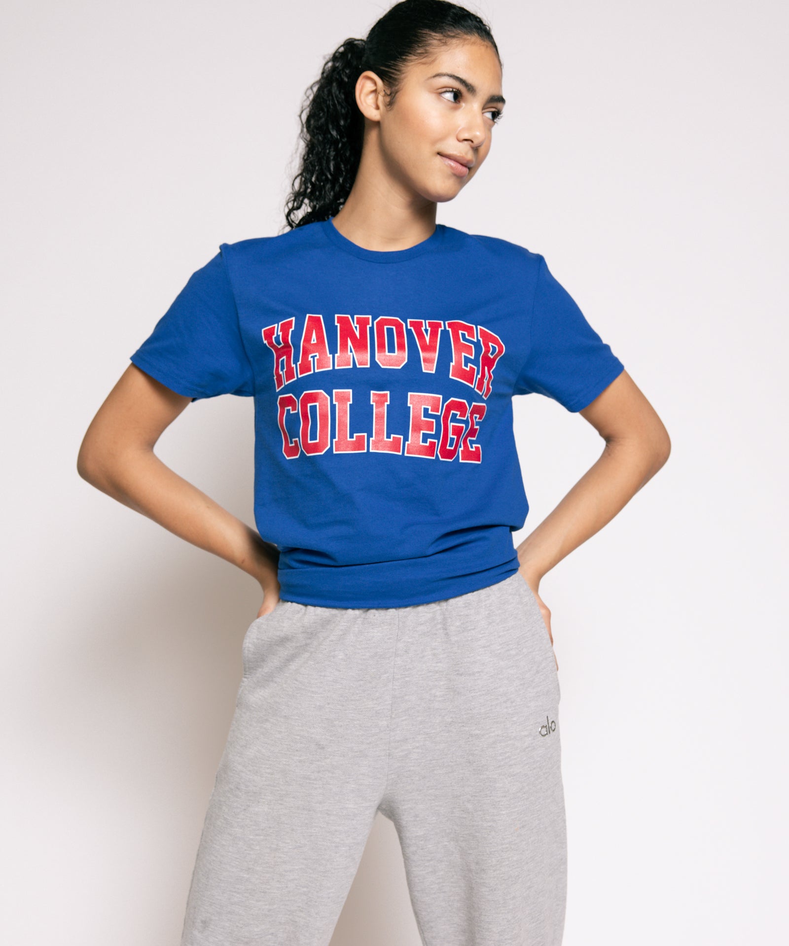 Person wearing a blue 'Hanover College' t-shirt and gray sweatpants on a white background