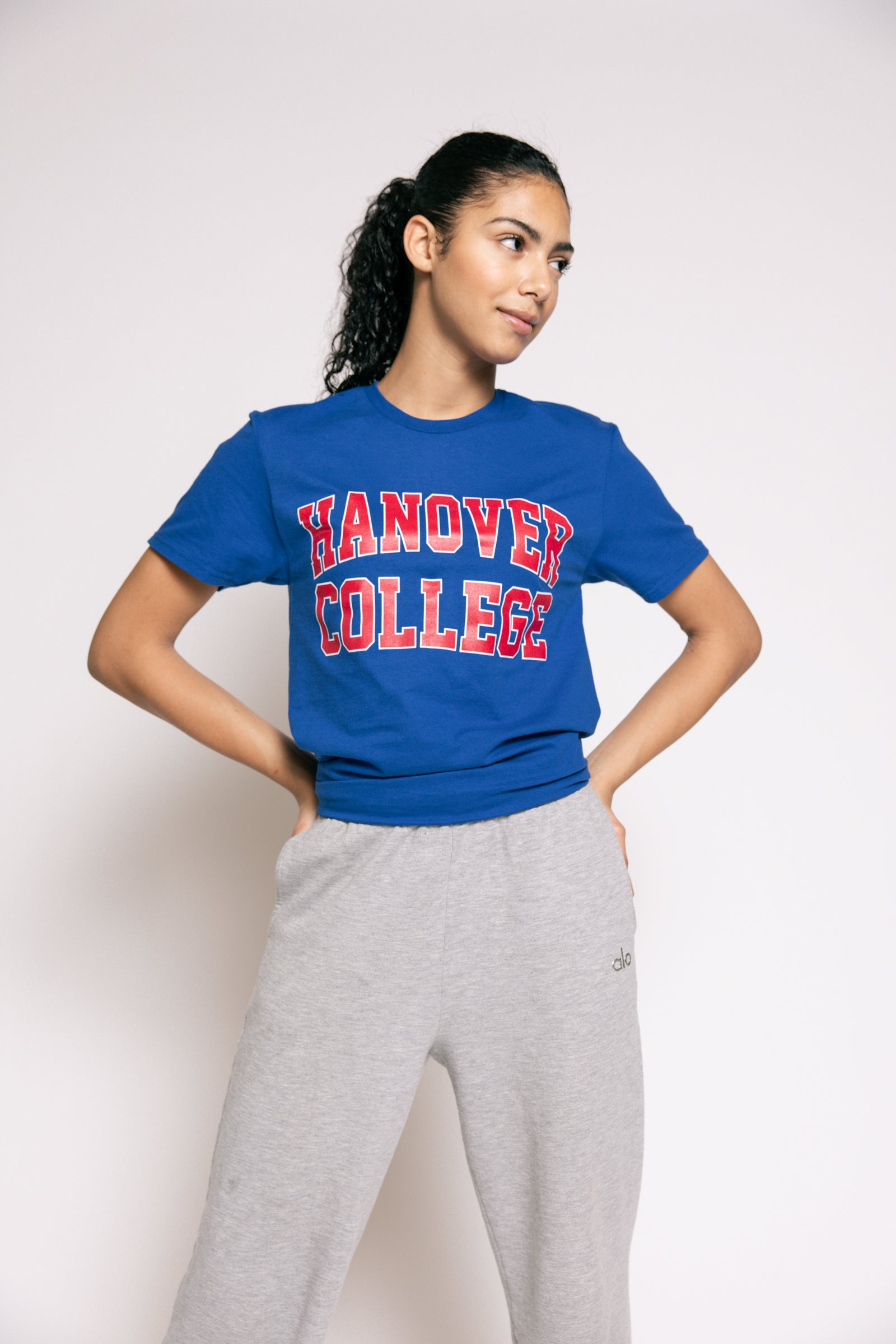 Person wearing a blue 'Hanover College' t-shirt and gray sweatpants on a white background